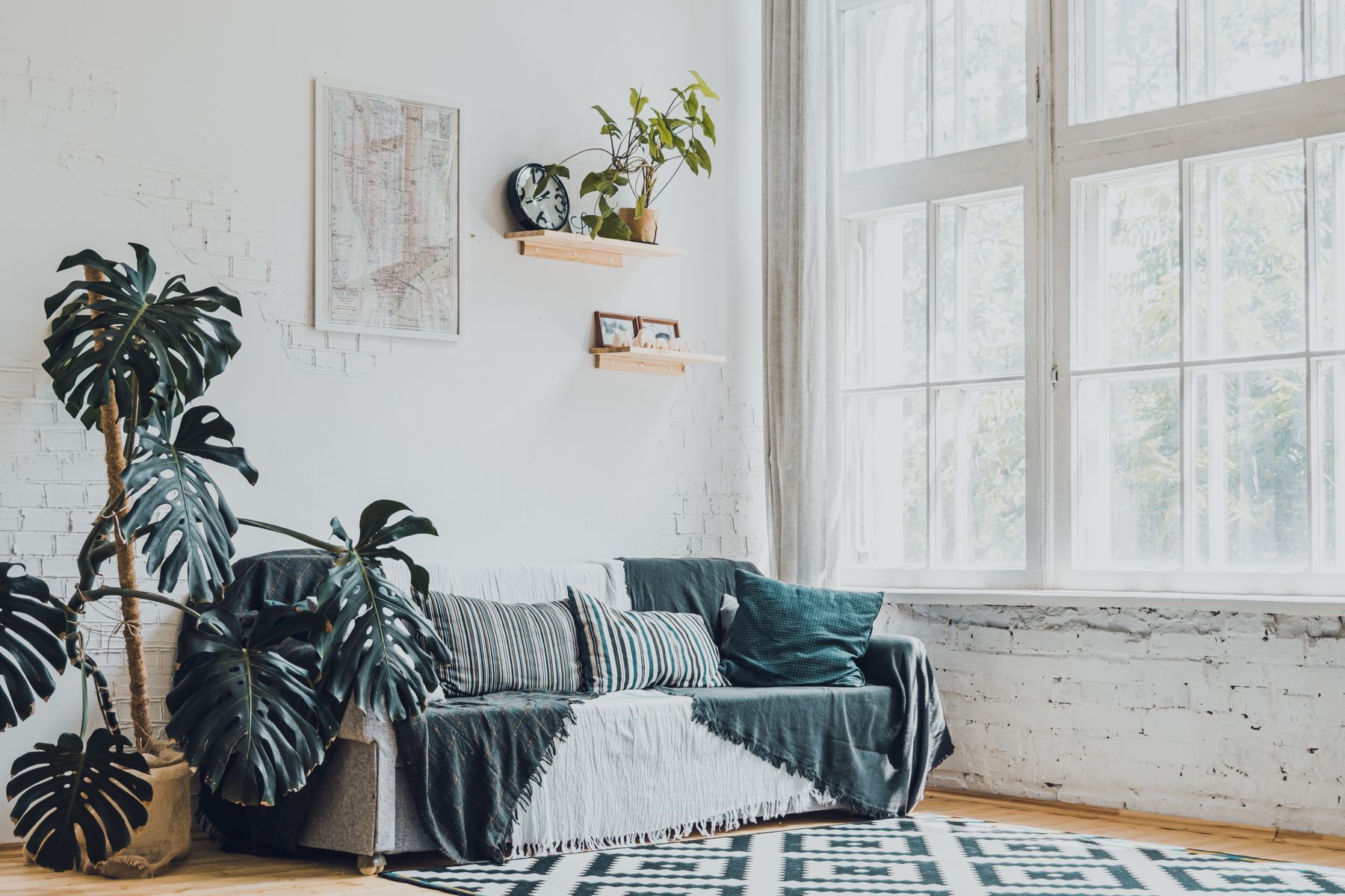 Lys stue med sofa, planter og store vinduer